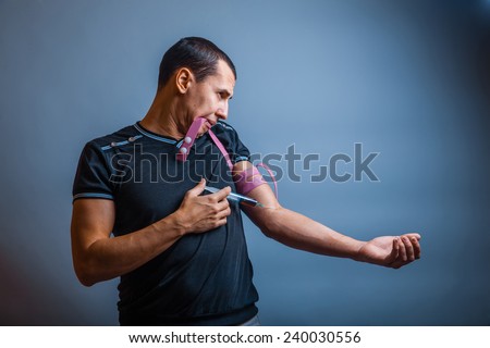 30 years old man of European appearance addict shooting up syringe on a gray background