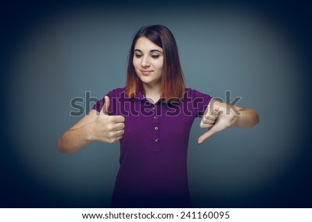 Girl 20 years of European appearance haired showing thumbs up sign yes  and no  on a gray background cross process