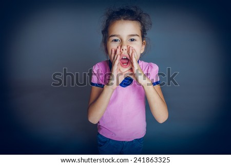 Girl Child Teen 7 years, European appearance brunette cries leaning his hands to his mouth on a gray background cross process