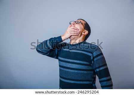 male of European appearance brunet covered his mouth with his hand and yawning, drowsiness