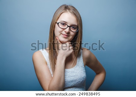 a girl of twenty European appearance blonde in glasses put a hand to his chin on a gray background, portrait