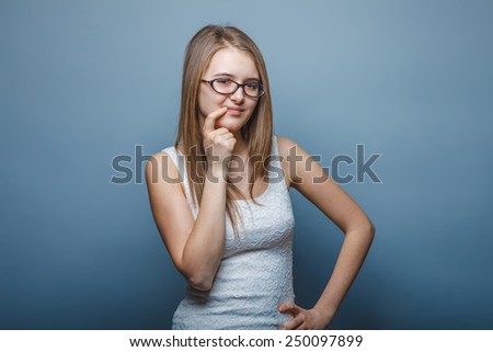 European appearance blonde girl with glasses hands on her waist smiling over gray background