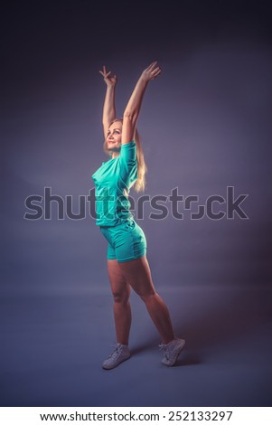 girl blonde European appearance raised her hands up on a gray background, charge, sports retro