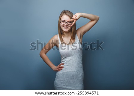 European-looking girl of twenty years in glasses showing two fingers, the victory on a gray background