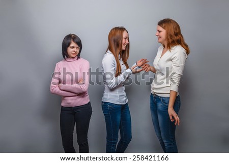 Three girls girlfriends talking two, one was offended on a gray background