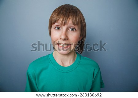 Boy, teenager, twelve years in a green T-shirt, showing teeth surprise