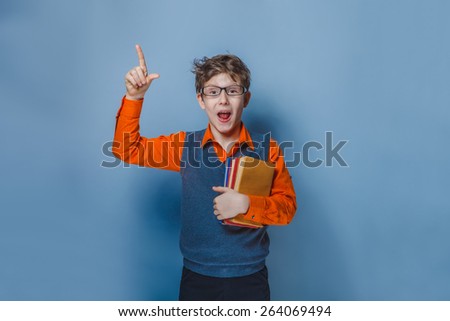 European-looking  boy of ten years  in glasses thumbs up, the idea of the book on a gray background