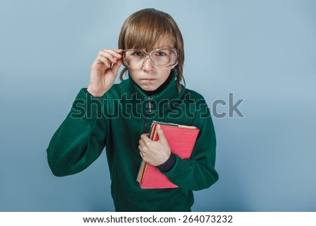 European-looking  boy  of ten years in glasses holding a book on a blue background