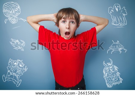 teenager boy in red T-shirt European appearance brown hair opened his mouth keeps his hands at his face on a gray backgroundunexpectedness, surprise