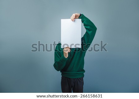 European-looking boy of ten years covered his face with a clean sheet on a  gray background