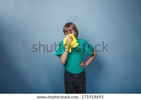 boy brown European appearance teenager in a green T-shirt and wrinkled blowing his nose into a handkerchief, illness