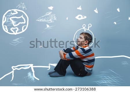 European appearance boy ten years dreaming sitting thinking on a gray background