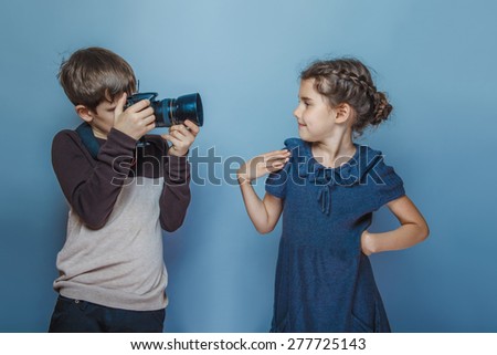 Boy teenager European appearance photographs teen girl on a gray background