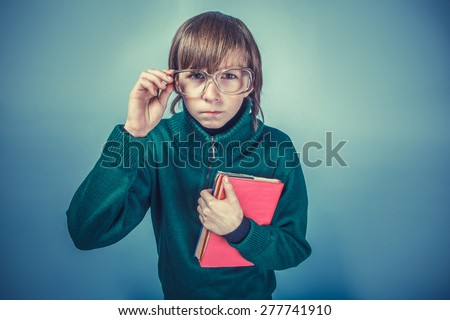 European-looking  boy  of ten years in glasses holding a book on a blue background instagram effect style