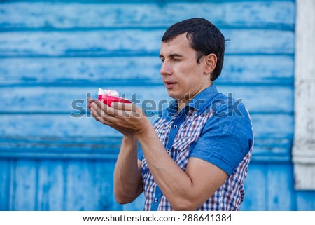 The man in the street holding a gift in a box on a blue background summer