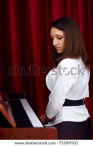 brunette woman looks at the piano