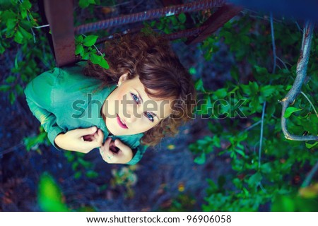 curly girl woman next old iron stairs nature of green background of foliage