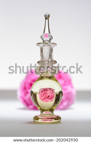 Small bottle with upside down image of rose that is lying behind the bottle
