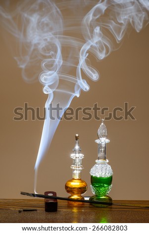 Small bottles of perfume dacorated with smoke from aromatic sticks