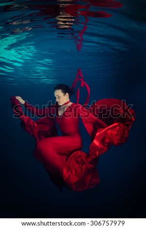 Young woman in red dress underwater with reflection