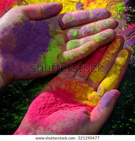 Womans hands covered with bright dry holi paint