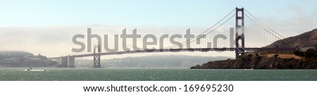 The Golden Gate Bridge shrouded in fog, as seen from the middle of San Francisco Bay.