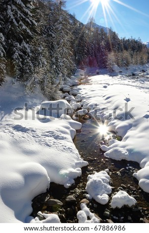 Sun mirroring on mountain stream in winter