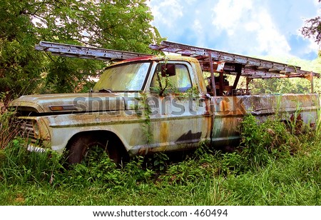 Rusty, vine covered work truck left where it died in the pasture in Kentucky, USA.