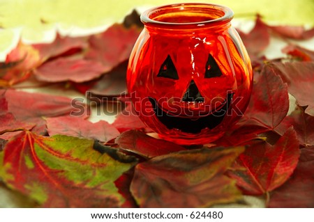 Halloween Smile - A glass jack o lantern sitting in a pile of  autumn leaves.
