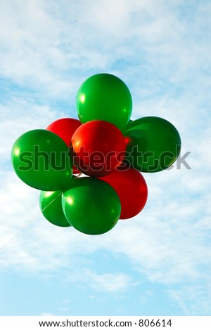 Red and Green Christmas colored balloons fly toward the sky.