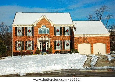 Two story brick American house in the suburbs in winter.  Decorated for the Christmas holidays.