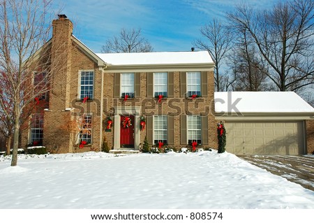 Two story brick American house sitting under a brilliant deep blue sky in winter.  Decorated for the Christmas holiday season.