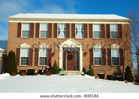 Two story brick American house sitting under a brilliant deep blue winter sky.  Decorated for the Christmas holiday season.