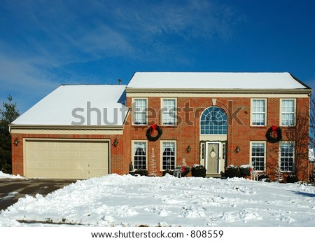 Two story brick American house in the suburbs in winter.  Decorated for the Christmas holiday season.