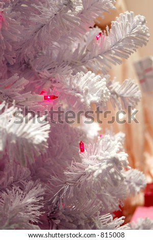 A snow white flocked Christmas tree with pink lights.