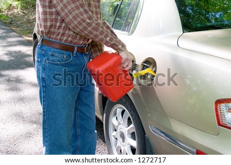 A man pouring gasoline into his tank from a red gas can.