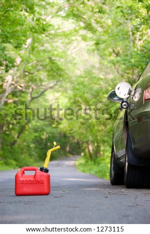 A red plastic gas can sitting in the middle of a country road next to a stranded car.
