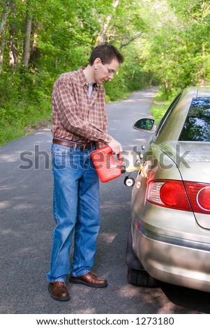 A man pouring gasoline into the gas tank of his car from a red gas can.  He\'s standing on a country road in the middle of nowhere, lost.