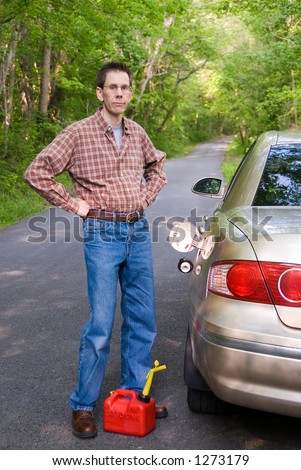 Upset man holding a gas can on a country road, staring  at the empty gas tank of his car.