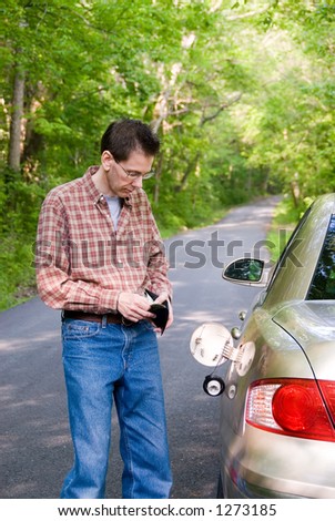Upset man on a country road, staring in his wallet to see if he has the money to fill the empty gas tank of his car and pay for the tow truck when it arrives.