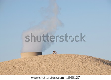 A girl sits on top of a Lake Michigan sand dune overlooking the smoke stack of a coal power plant.