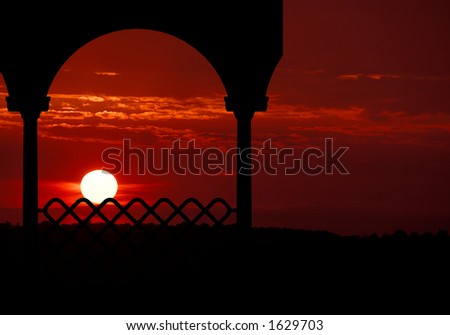 The sun sets in brilliant shades of red and orange and places the gazebo in silhouette.