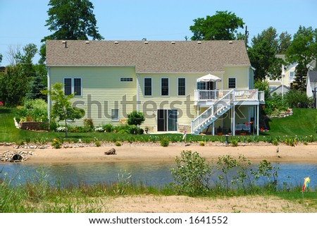 Beach House in Summer - Two story house in the suburbs showing the back yard with it\'s own pond.