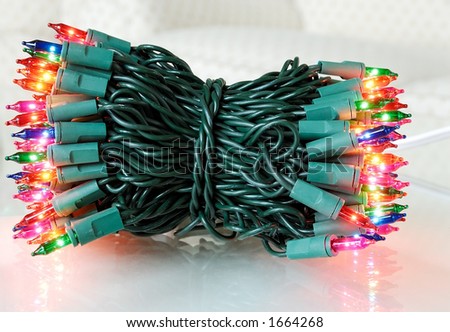 A colorful bundle of christmas tree lights on a reflective surface.