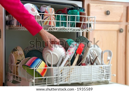 Washing Dishes - A female hand is shown loading dishes into the dishwasher.