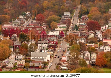 River Town USA - Aerial view of autumn in a small Kentucky river town. Two children ride bikes on the top of the grass covered floodwall between the town and the Ohio River.