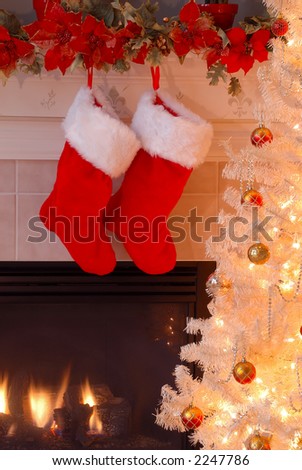 Two red fur stockings hang on the mantle over the fireplace as an antique lighted Christmas tree glows in the evening light.