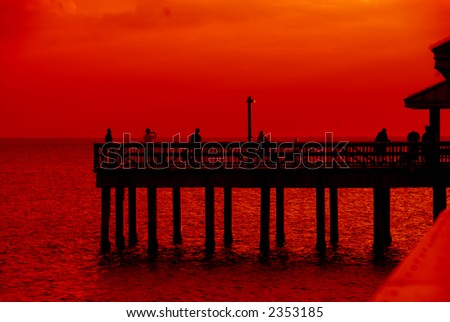 Sunset, Gulf of Mexico - A brilliant red and orange sunset over the water of the Gulf of Mexico at Ft Meyers Beach in December, watched by people standing on the pier.