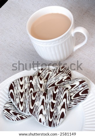 Chocolate Heart Cookies and Vanilla Cappuccino - White and dark chocolate heart shaped cookies on a white plate and a cup of vanilla cappucino.