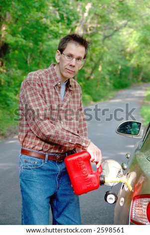 Out Of Gas On A Country Road - A man pours gasoline from a red plastic gas can into the tank of his car along a country road.